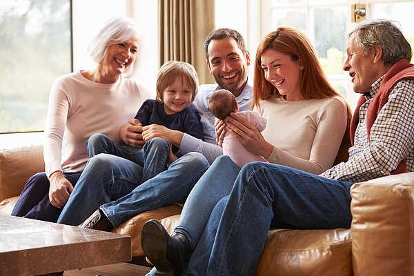 A mother, father, grandmother, grandfather and brother all looking at the new born baby.